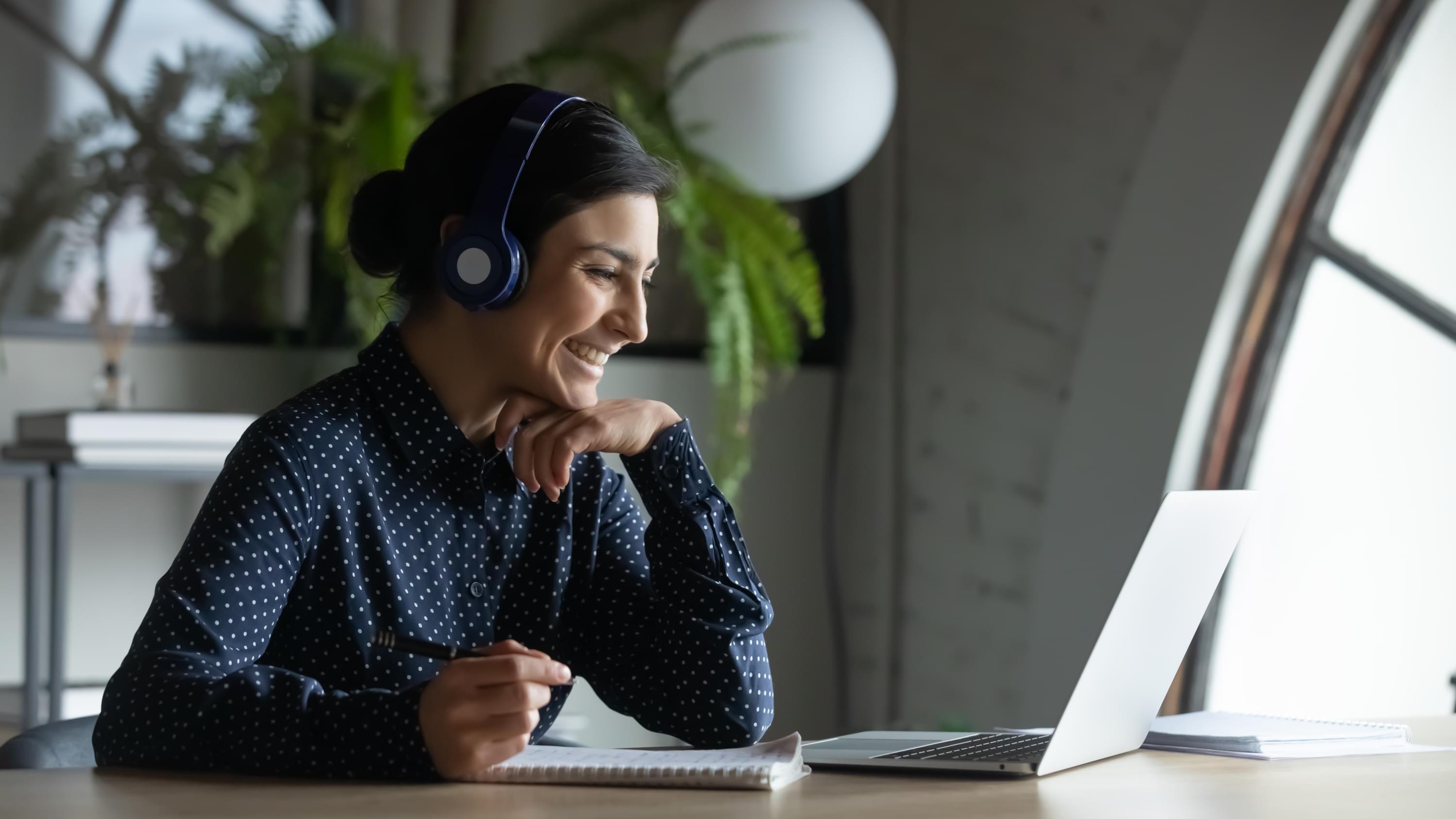 woman looking at laptop with headphones on